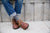 man, sitting, wearing blue jeans with rolled cuff, striped socks, wearing brown North Pacific handmade leather shoes by Aurora Shoe Co.
